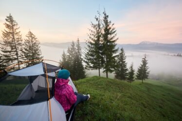 Kvinna utanför tält som njuter av utsikten